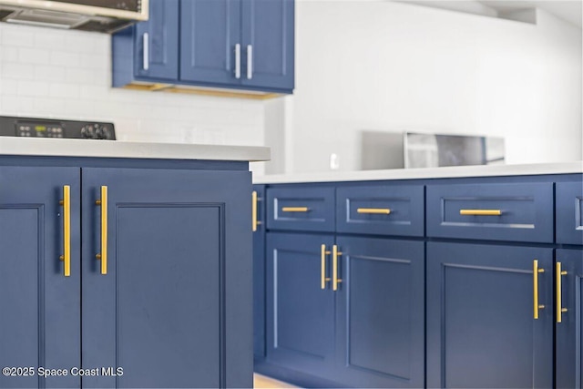 1709 Palm Ridge Rd, Melbourne, FL 32935 - kitchen view of blue cabinetry, light countertops, and decorative backsplash