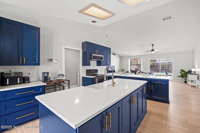 1709 Palm Ridge Rd, Melbourne, FL 32935 - kitchen with stainless steel appliances, blue cabinets, vaulted ceiling, tasteful backsplash, and light countertops