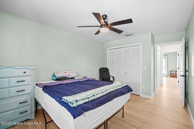 1709 Palm Ridge Rd, Melbourne, FL 32935 - bedroom featuring light wood-type flooring, a closet, baseboards, ceiling fan, and a textured ceiling