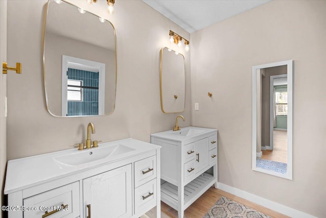 1709 Palm Ridge Rd, Melbourne, FL 32935 - bathroom featuring two vanities, wood finished floors, and baseboards