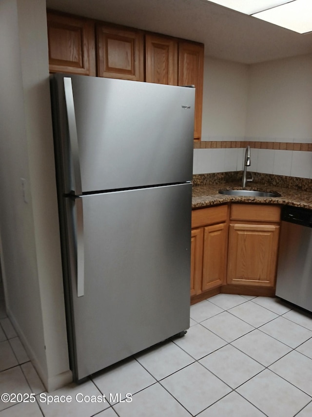 1600 Sunny Brook Ln NE Unit F106, Palm Bay, FL 32905 - kitchen with stainless steel appliances, a sink, dark countertops, brown cabinets, and light tile patterned floors