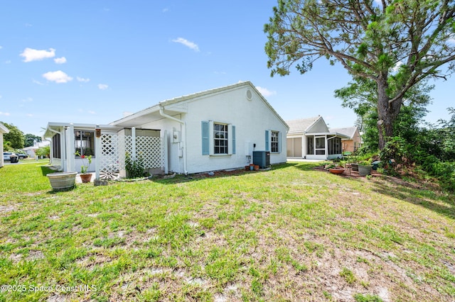 1924 Elderberry Ct NE, Palm Bay, FL 32905 - back of house featuring a sunroom, a lawn, central AC, and stucco siding