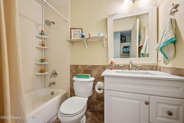 1924 Elderberry Ct NE, Palm Bay, FL 32905 - bathroom featuring toilet, shower / bath combo with shower curtain, tile walls, vanity, and wainscoting