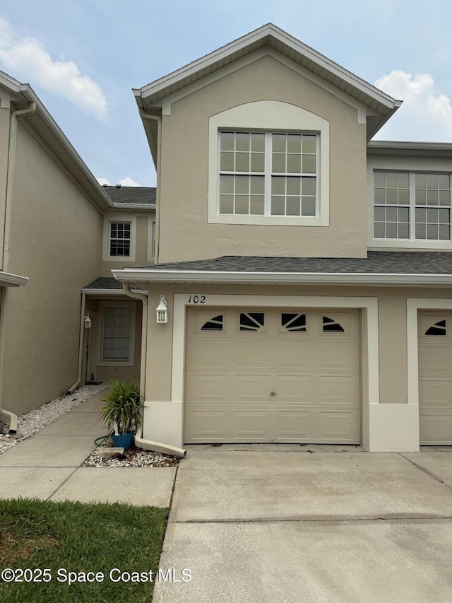 601 Trotter Ln Unit 102, Melbourne, FL 32940 - view of front of home featuring stucco siding, an attached garage, concrete driveway, and a shingled roof