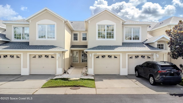 601 Trotter Ln Unit 102, Melbourne, FL 32940 - view of front of property featuring a garage, driveway, stucco siding, and roof with shingles