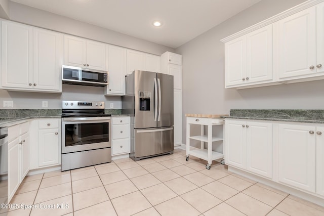 601 Trotter Ln Unit 102, Melbourne, FL 32940 - kitchen with appliances with stainless steel finishes, recessed lighting, white cabinetry, light tile patterned floors, and dark stone countertops