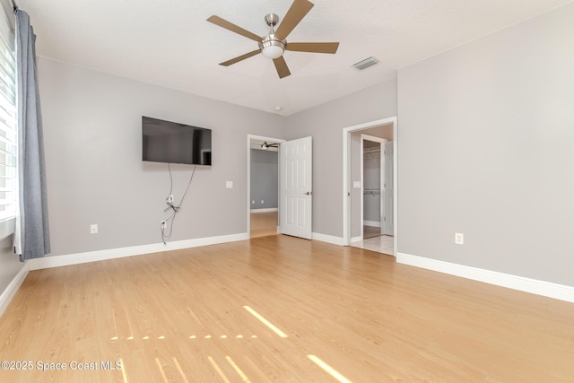 601 Trotter Ln Unit 102, Melbourne, FL 32940 - unfurnished bedroom with light wood finished floors, baseboards, a walk in closet, and a ceiling fan