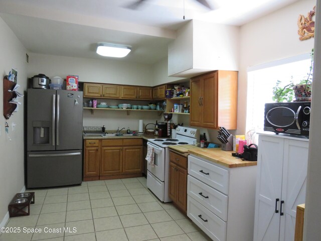 4535 Moon Rd, Titusville, FL 32780 - kitchen with stainless steel fridge, white electric range oven, open shelves, light tile patterned flooring, and a ceiling fan