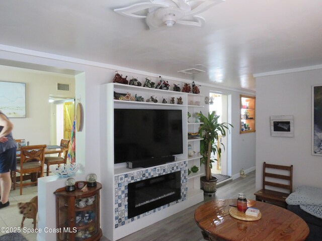 4535 Moon Rd, Titusville, FL 32780 - living area featuring a ceiling fan, a glass covered fireplace, and crown molding