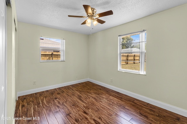 7034 Bayfront Rd, Cocoa, FL 32927 - empty room with dark wood finished floors, healthy amount of natural light, a textured ceiling, a ceiling fan, and baseboards