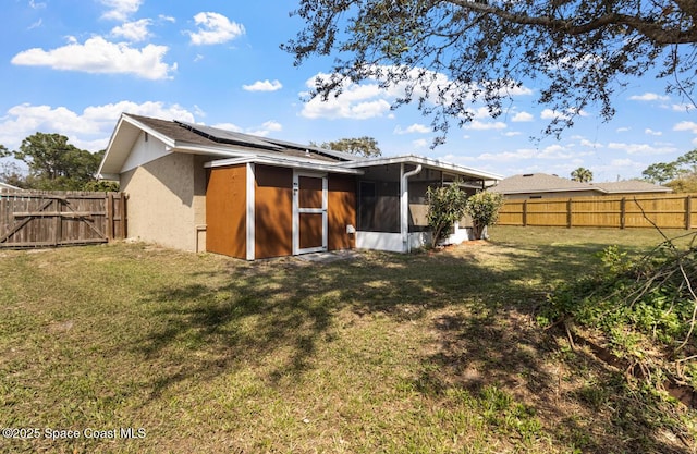 7034 Bayfront Rd, Cocoa, FL 32927 - rear view of property featuring roof mounted solar panels, a sunroom, stucco siding, and a gate
