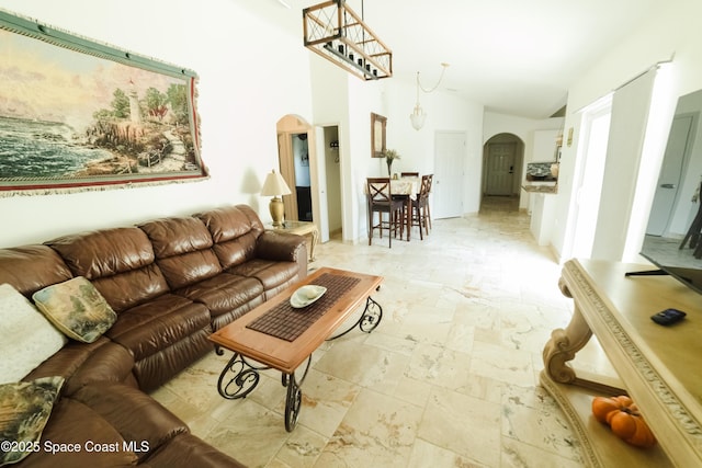 living room with arched walkways, lofted ceiling, and stone tile floors