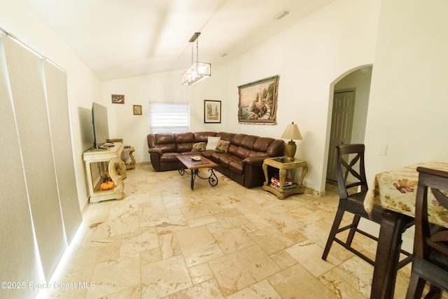 living area featuring arched walkways, stone tile flooring, and lofted ceiling