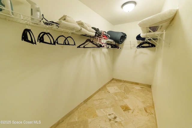 spacious closet featuring light stone finish floors