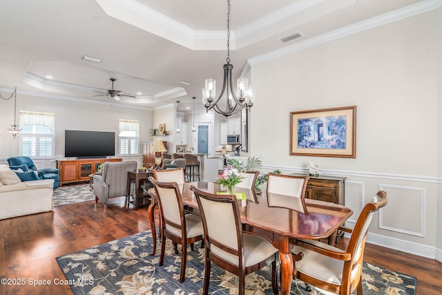 508 Lorelei Ave, Melbourne, FL 32901 - dining area with a tray ceiling, a chandelier, dark wood finished floors, a ceiling fan, and ornamental molding