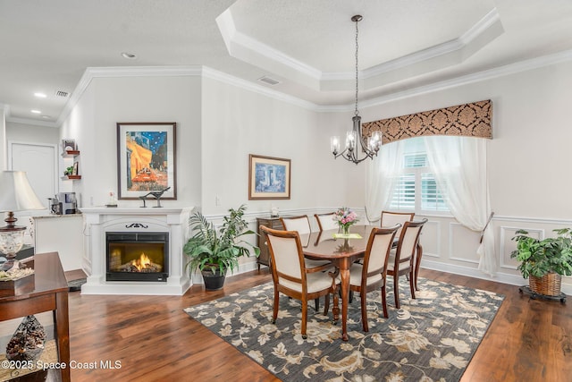 508 Lorelei Ave, Melbourne, FL 32901 - dining room with wood finished floors, a chandelier, a tray ceiling, crown molding, and a warm lit fireplace