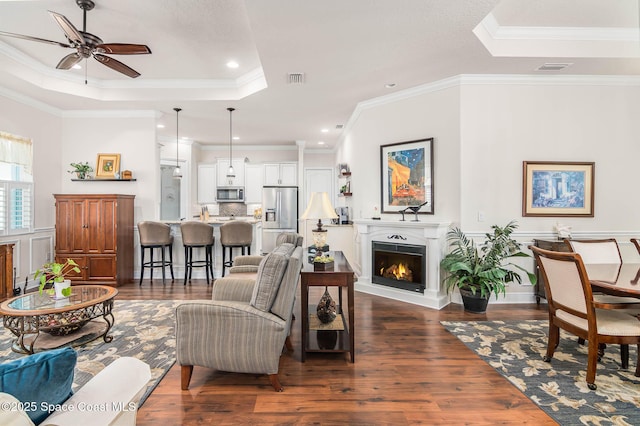 508 Lorelei Ave, Melbourne, FL 32901 - living room with a tray ceiling, dark wood finished floors, a ceiling fan, a warm lit fireplace, and ornamental molding