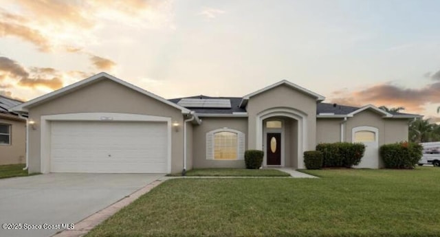 1932 Laramie Cir, Melbourne, FL 32940 - view of front of house with stucco siding, an attached garage, solar panels, driveway, and a yard
