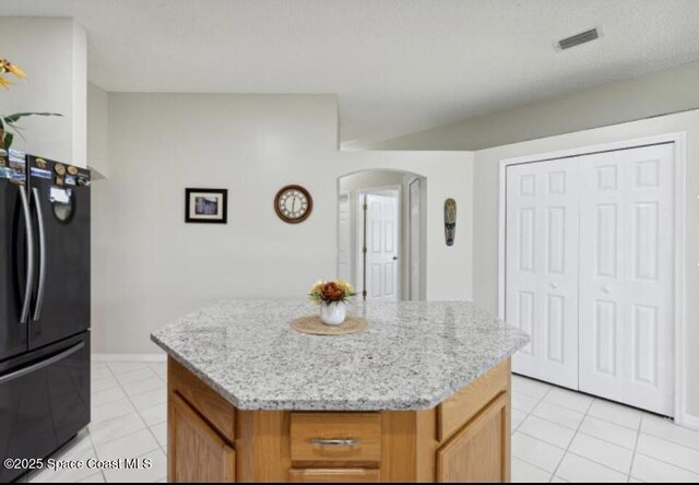 1932 Laramie Cir, Melbourne, FL 32940 - kitchen with freestanding refrigerator, arched walkways, light tile patterned floors, a kitchen island, and baseboards
