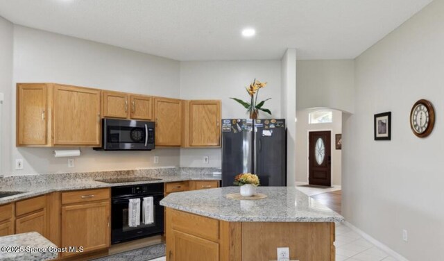 1932 Laramie Cir, Melbourne, FL 32940 - kitchen featuring black appliances, light stone countertops, a kitchen island, light tile patterned floors, and arched walkways