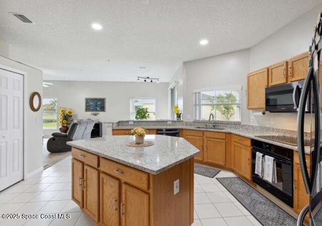 1932 Laramie Cir, Melbourne, FL 32940 - kitchen featuring black appliances, a sink, a center island, light stone countertops, and open floor plan