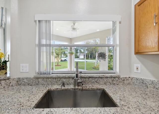 1932 Laramie Cir, Melbourne, FL 32940 - kitchen view of a sink, light stone counters, and a ceiling fan