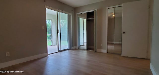 3143 Sir Hamilton Cir Unit 12, Titusville, FL 32780 - unfurnished bedroom featuring two closets, light wood-style floors, and baseboards