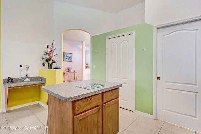 427 Falls Church St SW, Palm Bay, FL 32908 - kitchen with light tile patterned floors, arched walkways, a kitchen island, and baseboards