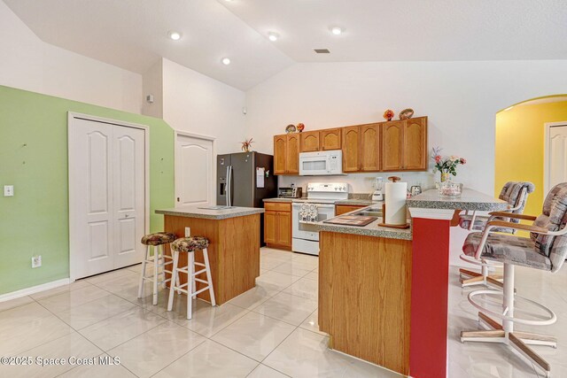 427 Falls Church St SW, Palm Bay, FL 32908 - kitchen featuring white appliances, arched walkways, a kitchen bar, high vaulted ceiling, and brown cabinetry