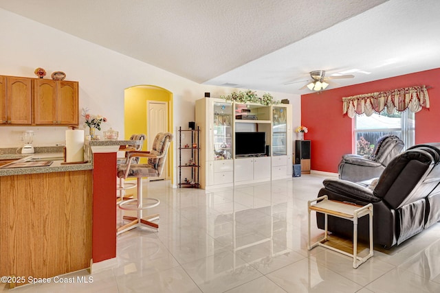 427 Falls Church St SW, Palm Bay, FL 32908 - living area with arched walkways, ceiling fan, a textured ceiling, baseboards, and light tile patterned floors