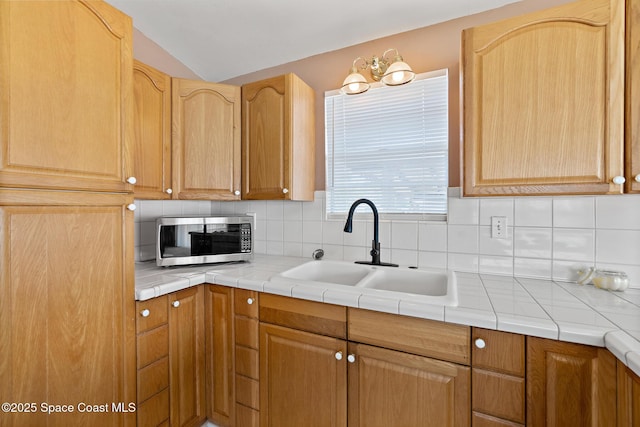 4545 Tina St, Cocoa, FL 32927 - kitchen featuring stainless steel microwave, a sink, decorative backsplash, lofted ceiling, and light brown cabinets