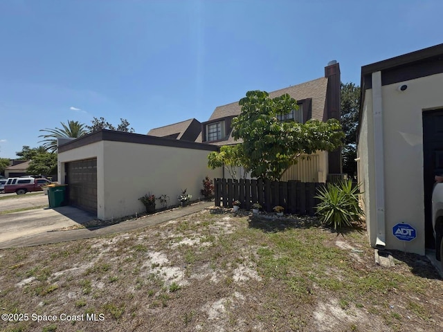 3454 Pheasant Ct, Melbourne, FL 32935 - view of side of property with stucco siding, fence, an attached garage, and concrete driveway