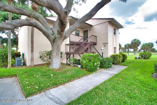 2550 Eagle Dr Unit 3-C, Melbourne, FL 32935 - view of home's exterior with stucco siding, a yard, stairway, and cooling unit