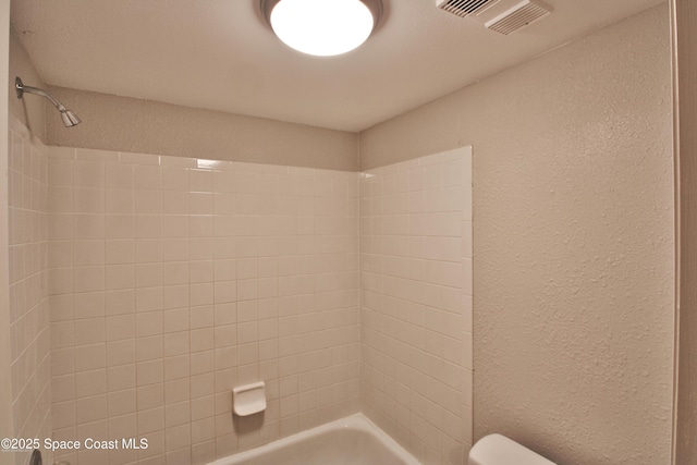 2550 Eagle Dr Unit 3-C, Melbourne, FL 32935 - bathroom featuring a textured wall, toilet, and shower / bath combination