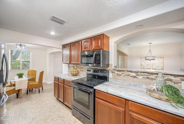 kitchen featuring stainless steel appliances, arched walkways, tasteful backsplash, light stone counters, and recessed lighting