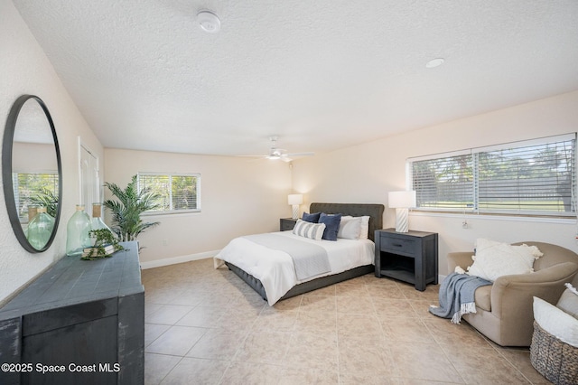 bedroom featuring light tile patterned flooring, a ceiling fan, a textured ceiling, and baseboards