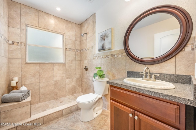 full bath featuring a tile shower, toilet, vanity, tile walls, and tile patterned floors