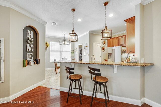 1409 Corbett Ln, Melbourne, FL 32904 - kitchen featuring fridge with ice dispenser, a breakfast bar area, crown molding, light stone countertops, and recessed lighting