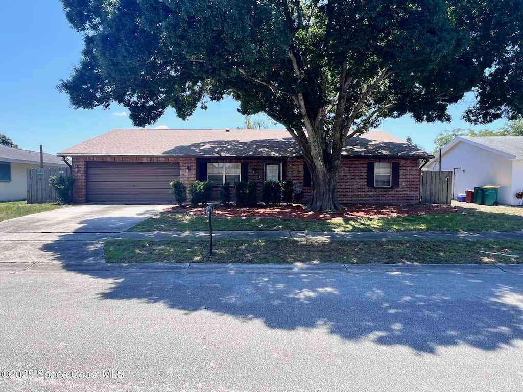 611 Tulane Ave, Melbourne, FL 32901 - ranch-style house with brick siding, concrete driveway, a garage, and fence