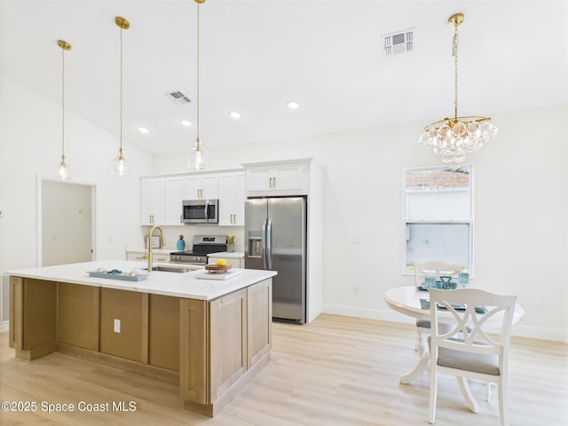 8116 97th Ct, Vero Beach, FL 32967 - kitchen with appliances with stainless steel finishes, a sink, light wood-style flooring, a kitchen island with sink, and white cabinets