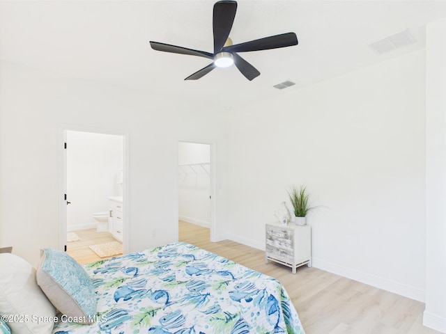 8116 97th Ct, Vero Beach, FL 32967 - bedroom featuring light wood finished floors, a walk in closet, ensuite bath, baseboards, and a ceiling fan