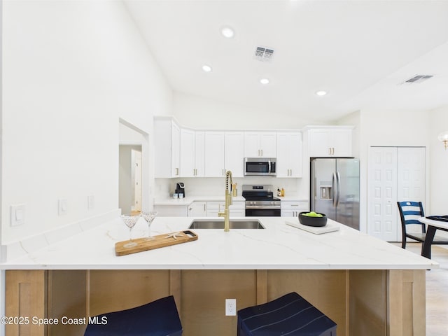 8126 97th Ave, Vero Beach, FL 32967 - kitchen with stainless steel appliances, a sink, a kitchen bar, light stone counters, and white cabinets