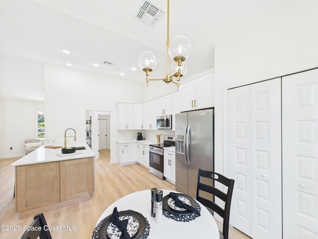 8126 97th Ave, Vero Beach, FL 32967 - kitchen featuring appliances with stainless steel finishes, a sink, light wood-style floors, a high ceiling, and a chandelier