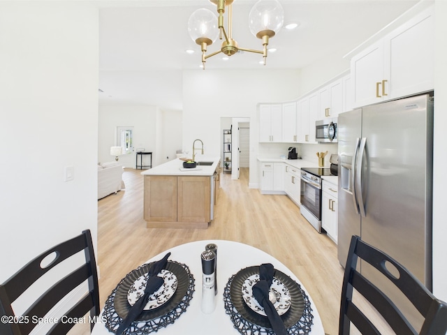 8126 97th Ave, Vero Beach, FL 32967 - kitchen featuring appliances with stainless steel finishes, light wood-type flooring, a sink, a chandelier, and white cabinetry