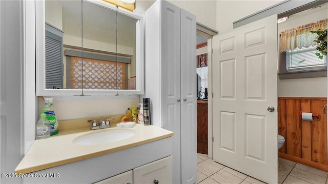 8516 99th Ct, Vero Beach, FL 32967 - bathroom featuring vanity, toilet, tile patterned floors, and a wainscoted wall
