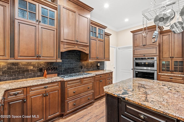 1197 Acappella Dr, Melbourne, FL 32940 - kitchen featuring appliances with stainless steel finishes, light wood-style floors, ornamental molding, tasteful backsplash, and light stone counters