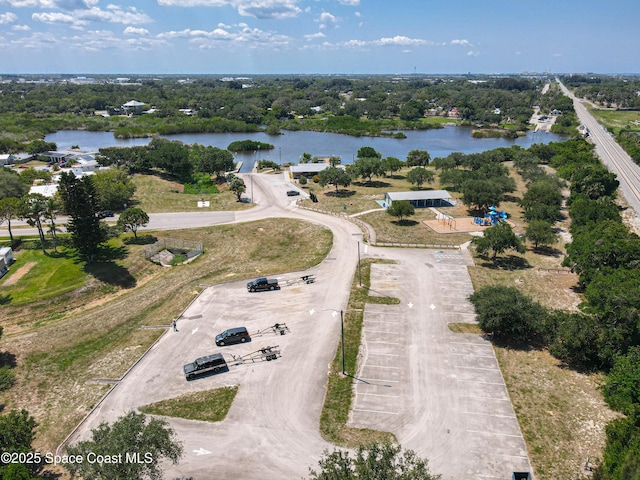 drone / aerial view of a nearby body of water and a tree filled landscape