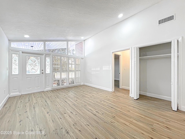 foyer with baseboards, light wood-style floors, a textured ceiling, and recessed lighting