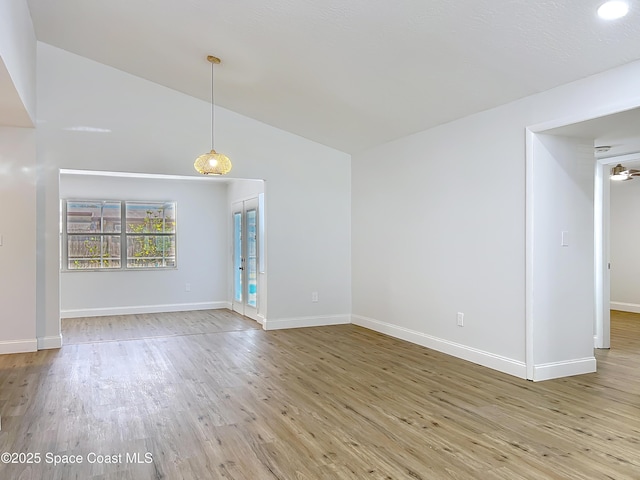 unfurnished living room with wood finished floors, lofted ceiling, and baseboards