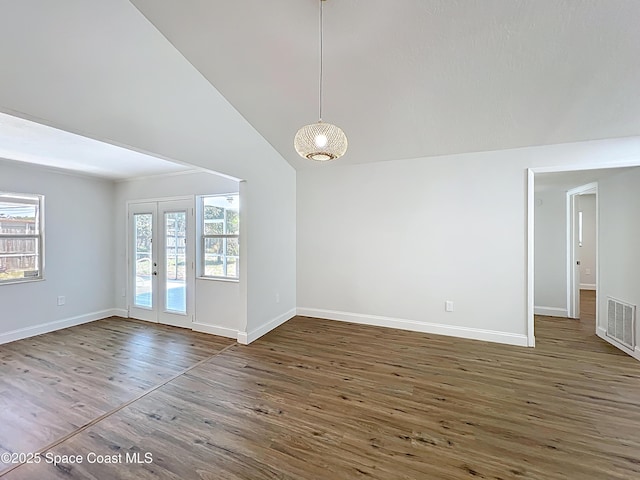 spare room featuring healthy amount of natural light, wood finished floors, baseboards, and high vaulted ceiling
